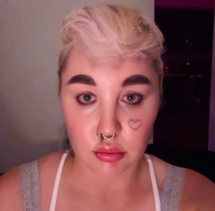 Person with short blonde hair and septum piercing, appearing serious in a dimly lit room discussing Amanda Bynes claim viral. Person with short blonde hair and septum piercing, appearing serious in a dimly lit room discussing Amanda Bynes claim viral.