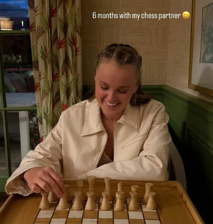 Young woman smiling and playing chess, illustrating JoJo Siwa's fans stunned and confused after Chris Hughes' reality TV confession. Young woman smiling and playing chess, illustrating JoJo Siwa's fans stunned and confused after Chris Hughes' reality TV confession.