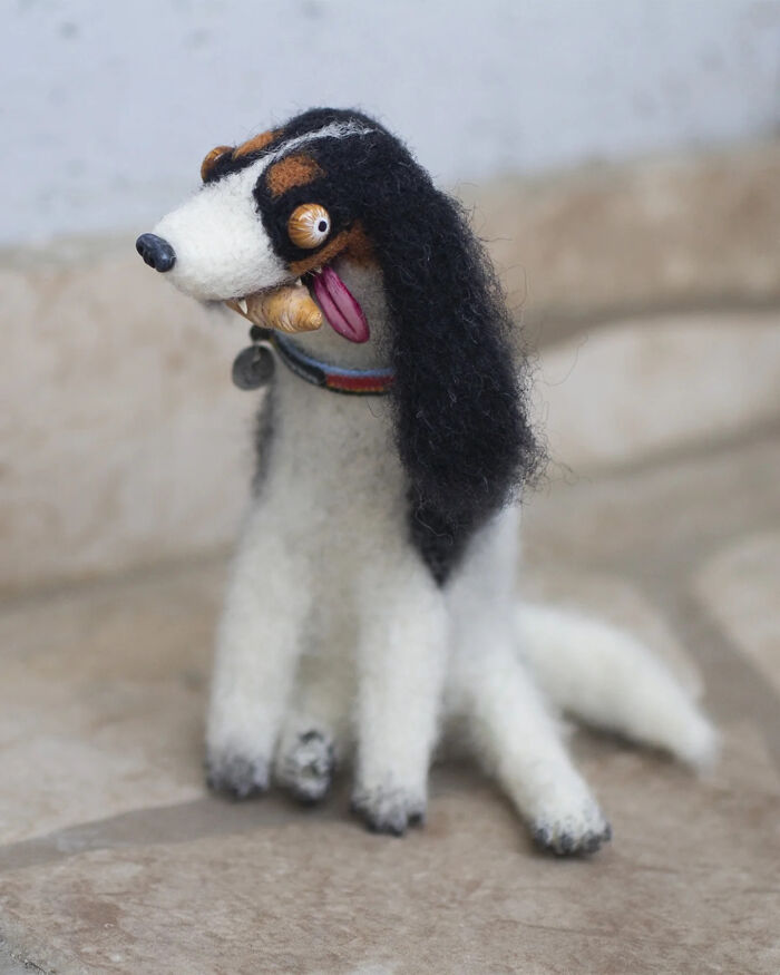 Handmade creature toy resembling a quirky dog with exaggerated eyes and textured black and white fur details.