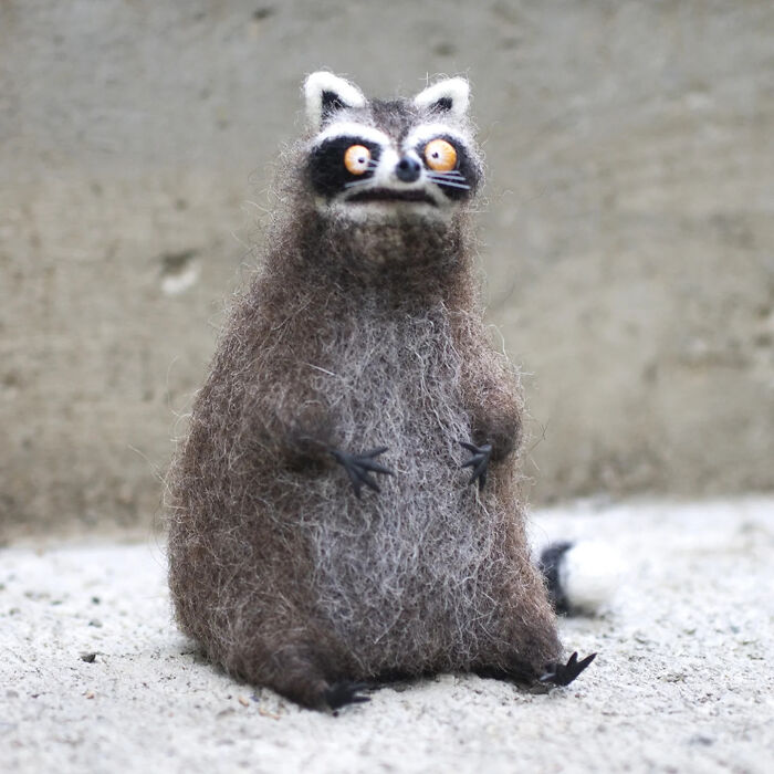 Handmade creature resembling a raccoon with fluffy gray fur and bright eyes, showcasing adorably strange toy art.