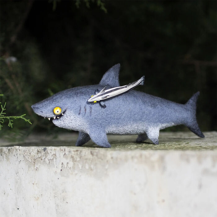 Handmade creature toy resembling a blue shark with a small fish attached, showcasing adorably strange artistic design.