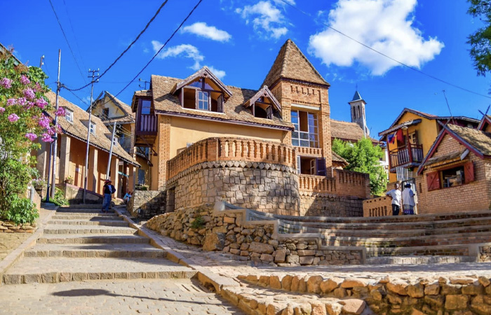 Traditional stone and brick houses in the poorest country in the world under a bright blue sky with scattered clouds.