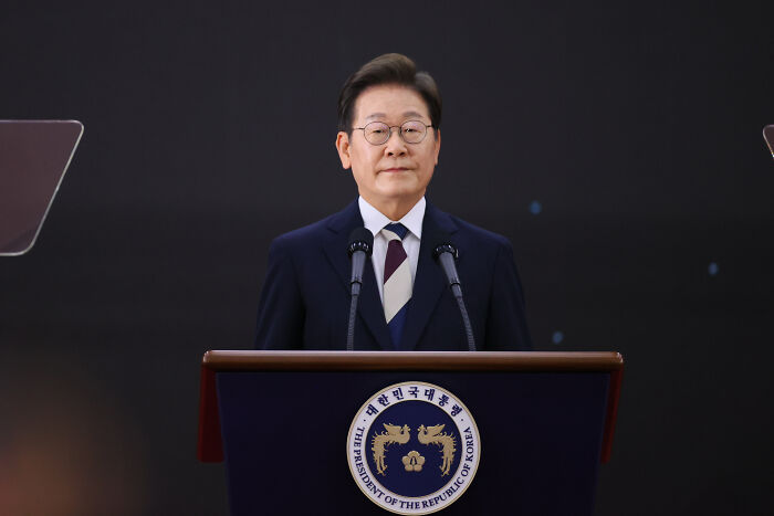 South Korean man known as world’s smartest standing at podium with presidential emblem, speaking publicly. South Korean man known as world’s smartest standing at podium with presidential emblem, speaking publicly.