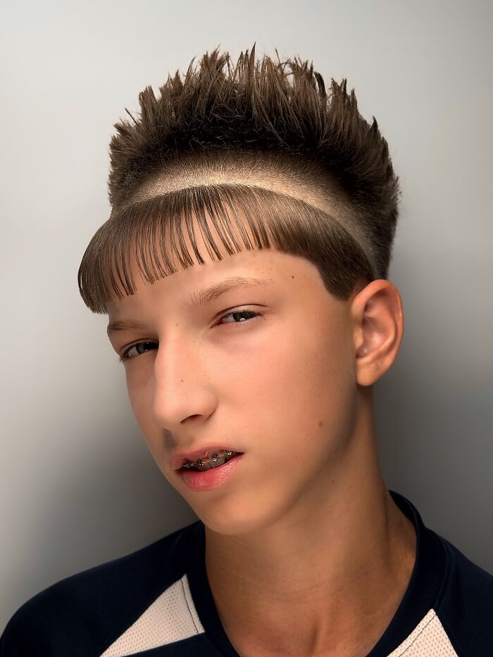 Teen boy with bold barber haircut featuring spiked top and distinct curved fringe line design on sides