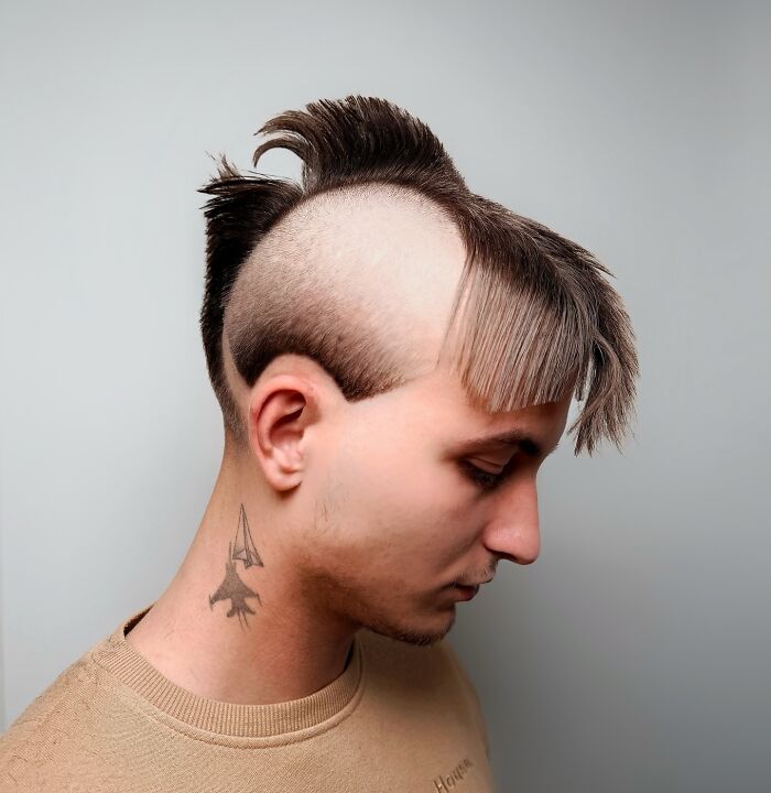 Young man with bold barber haircut featuring a shaved pattern and styled top hair in a modern look.