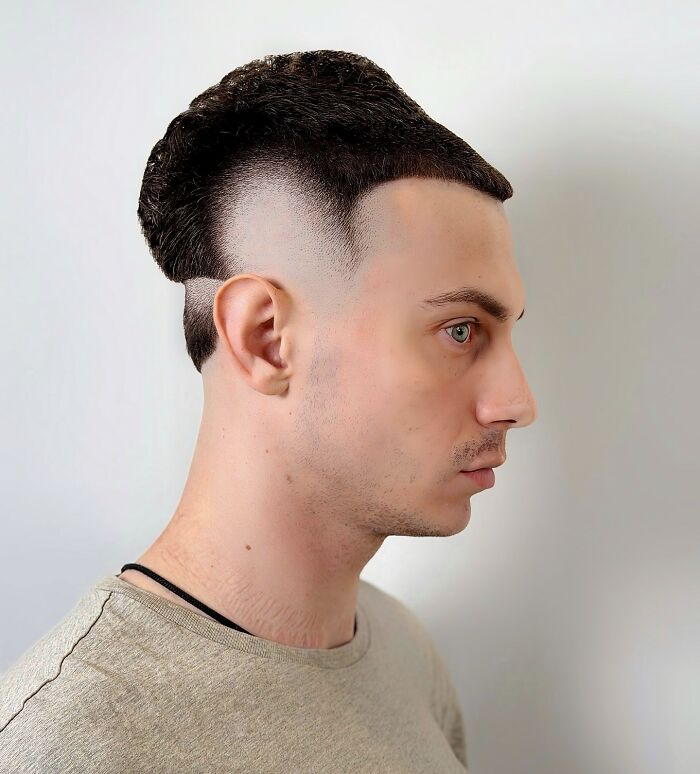 Young man with a bold barber haircut featuring a sharp fade and a unique textured top hairstyle in profile view Young man with a bold barber haircut featuring a sharp fade and a unique textured top hairstyle in profile view