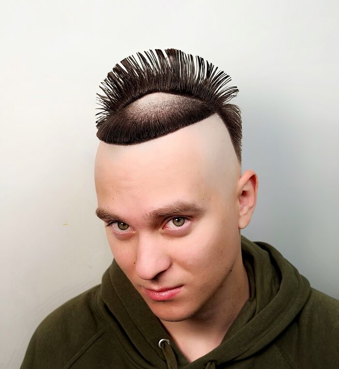 Young man with a bold barber haircut featuring a shaved head and styled spiked hair on top against a white background