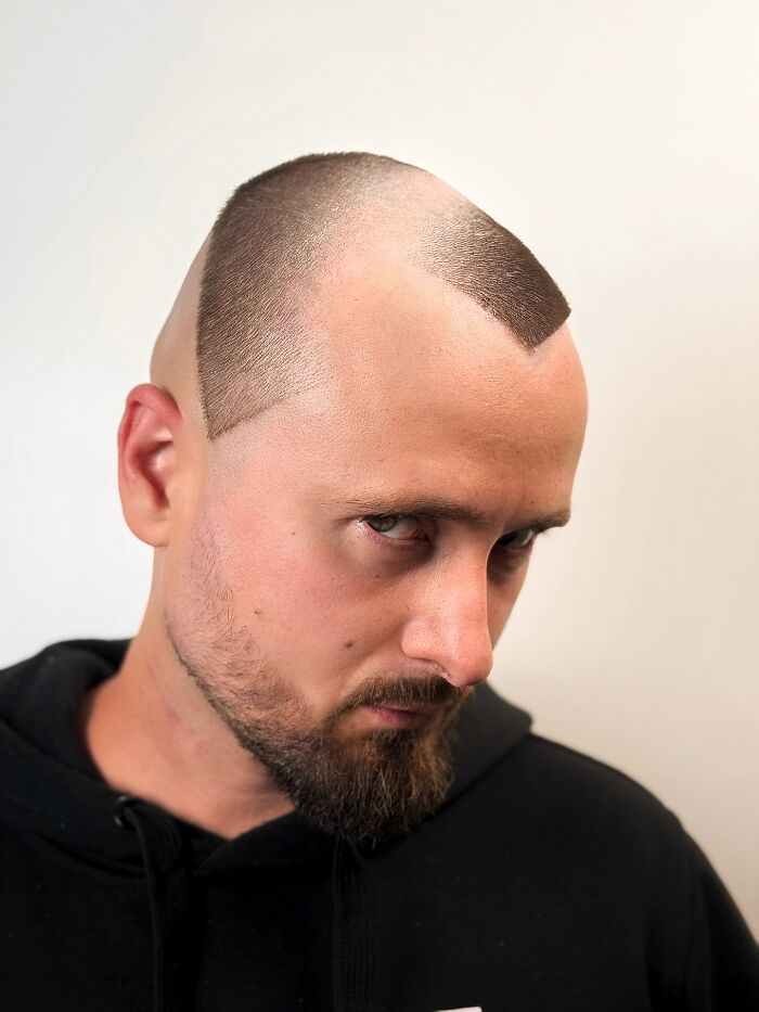 Man with a bold barber haircut featuring sharp geometric shapes and a distinctive high-contrast style in a close-up shot.