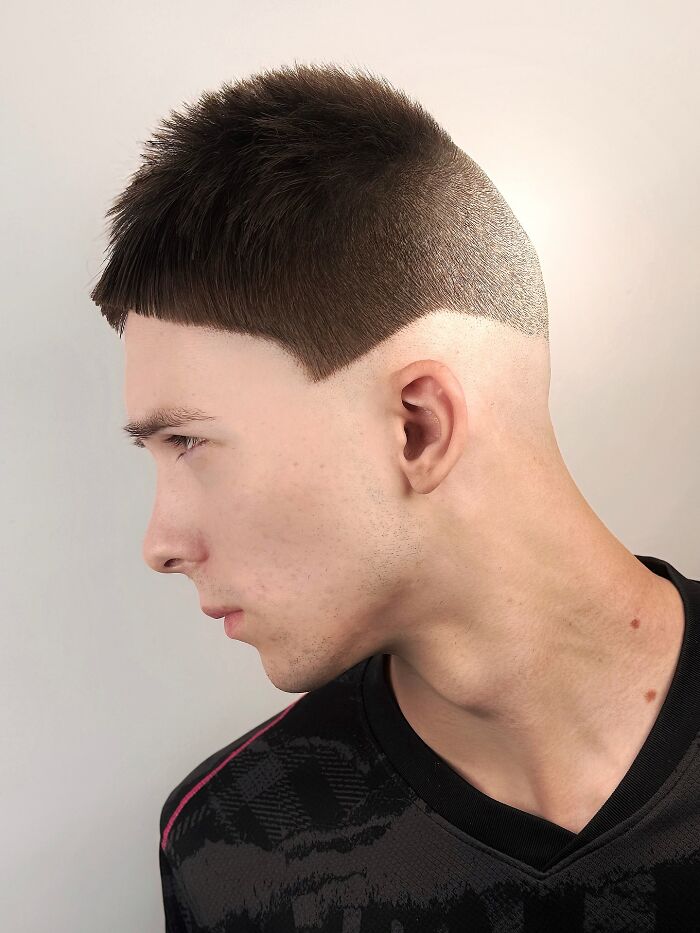 Side profile of a man with a bold barber haircut featuring a sharp geometric fade and textured top hair design.