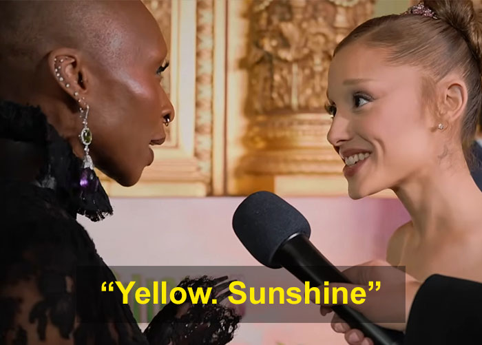 Cynthia Erivo and Ariana Grande in a close, intense interaction during an interview with a microphone between them. Cynthia Erivo and Ariana Grande in a close, intense interaction during an interview with a microphone between them.