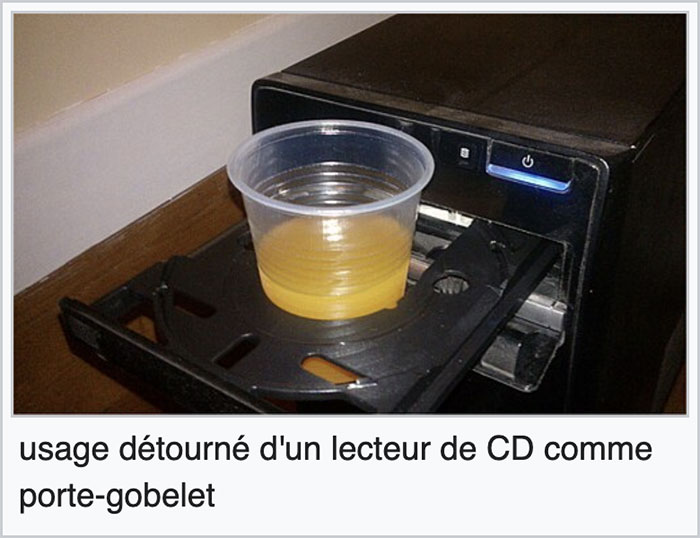 Plastic cup filled with juice placed on a CD drive tray, an unexpected funny gem found on Wikipedia new pics.