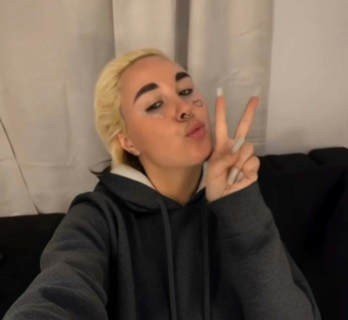 Amanda Bynes posing indoors wearing a dark hoodie, making a peace sign with her fingers and a playful expression. Amanda Bynes posing indoors wearing a dark hoodie, making a peace sign with her fingers and a playful expression.