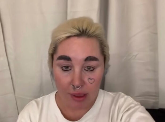 Amanda Bynes speaking in a video with a heart tattoo on her cheek and bleached hair against a white curtain background Amanda Bynes speaking in a video with a heart tattoo on her cheek and bleached hair against a white curtain background