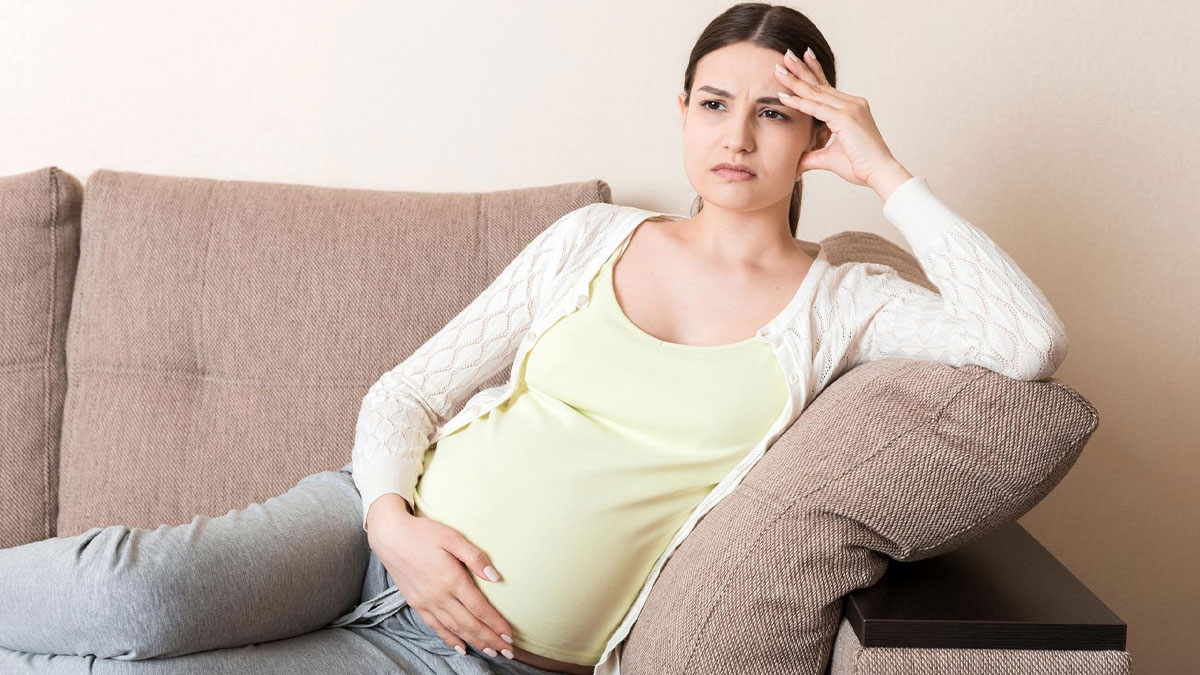 Pregnant woman sitting on a couch looking offended, related to pregnant SIL offended and air mattress dispute.