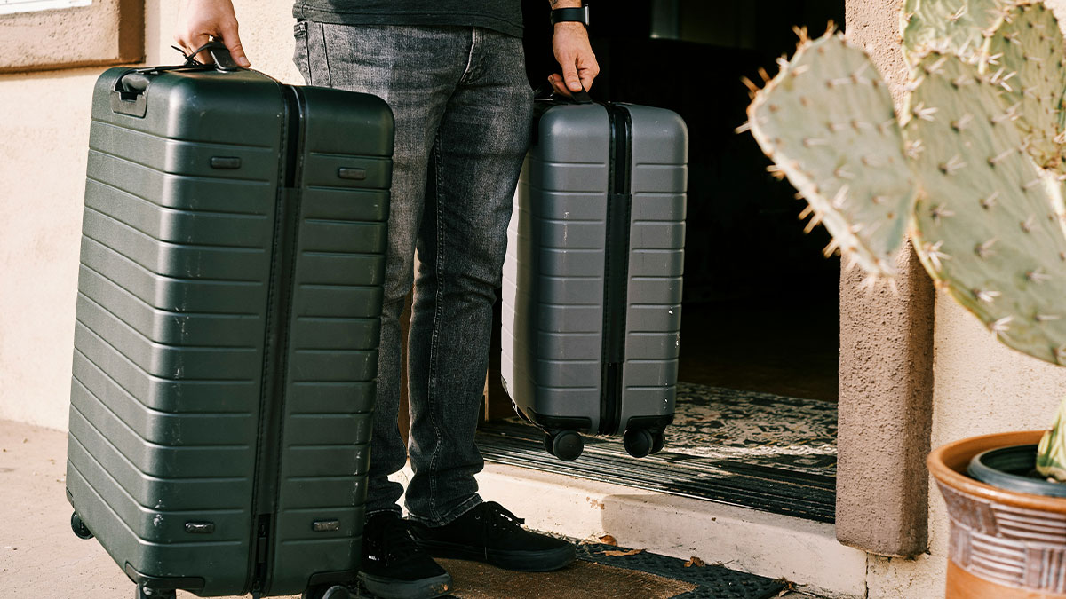 Person standing at a door holding two suitcases, illustrating a sister arriving to move in refusing entry scenario.