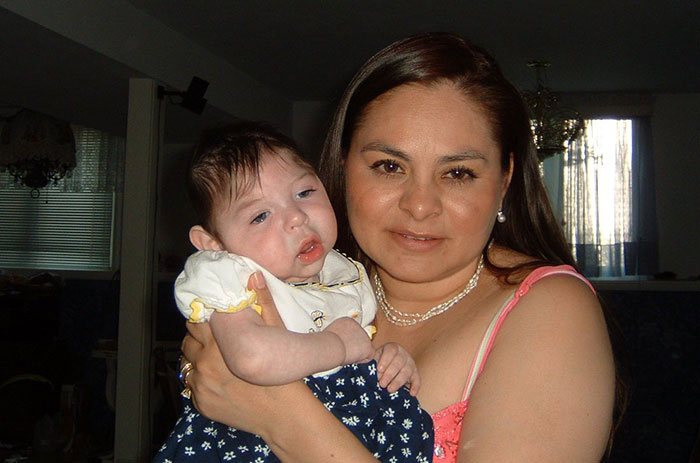 Woman holding baby born without most of her brain, highlighting rare medical condition with family in home setting Woman holding baby born without most of her brain, highlighting rare medical condition with family in home setting