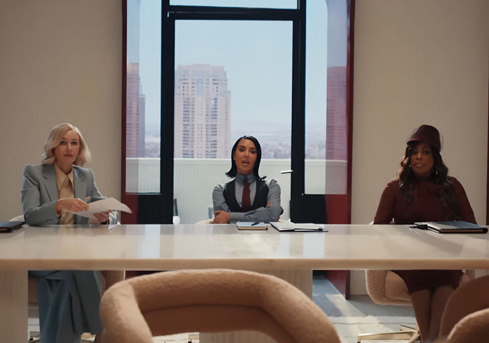 Three women sitting at a modern conference table during the All's Fair premiere with Kim Kardashian in a bright office. Three women sitting at a modern conference table during the All's Fair premiere with Kim Kardashian in a bright office.