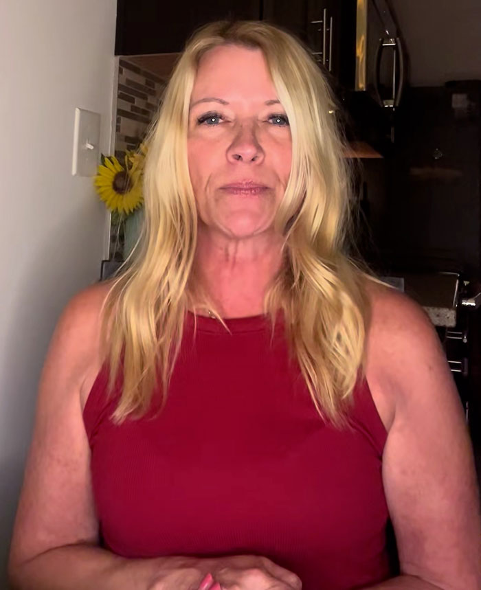Middle-aged woman with long blonde hair wearing a red sleeveless top discussing bearded trans man in women’s restroom debate Middle-aged woman with long blonde hair wearing a red sleeveless top discussing bearded trans man in women’s restroom debate
