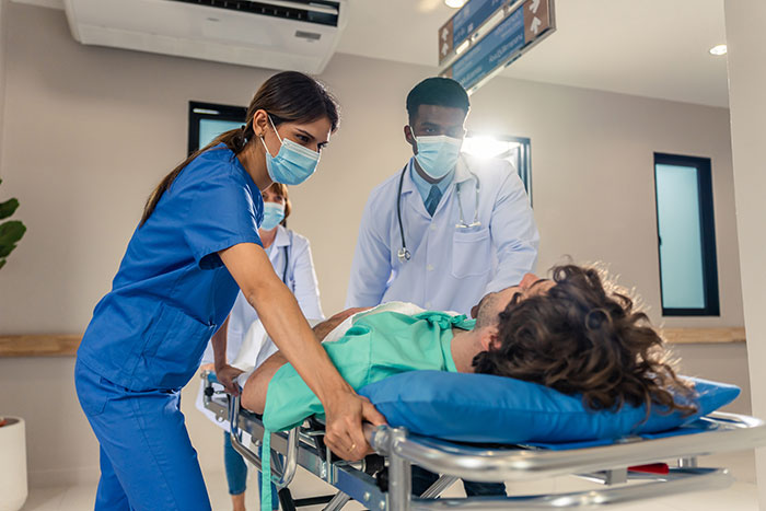 Medical staff wearing masks pushing a patient on a stretcher, highlighting issues to pay for ambulance rides in America.