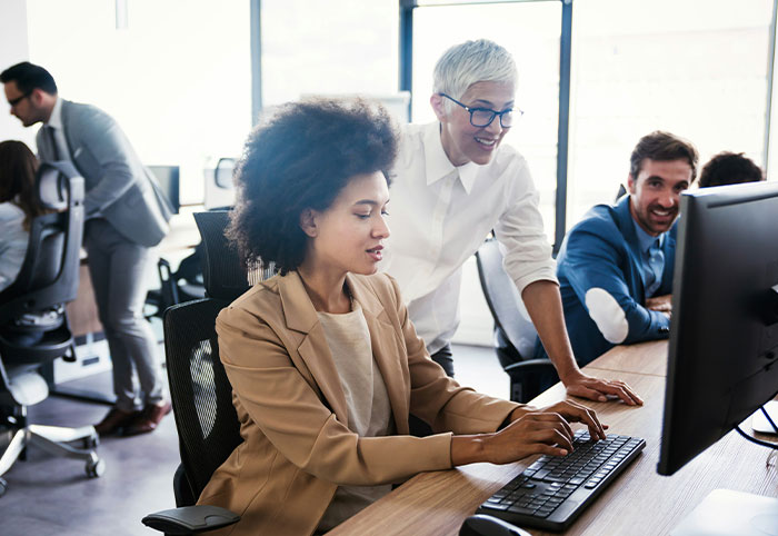 Two coworkers collaborating at a computer in an office, illustrating American expats adjusting to Canadian work culture.