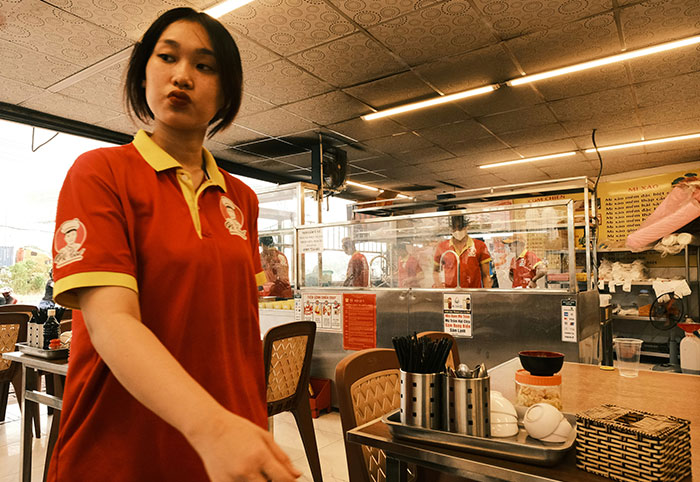 Woman in a red shirt working in a restaurant, highlighting cultural differences noticed by American expats in Canada.