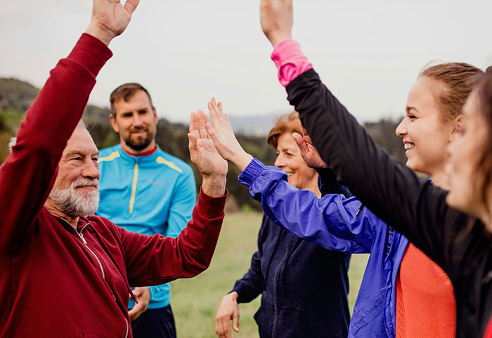 Group of American expats outdoors in Canada raising their hands, enjoying social interaction and cultural exchange.