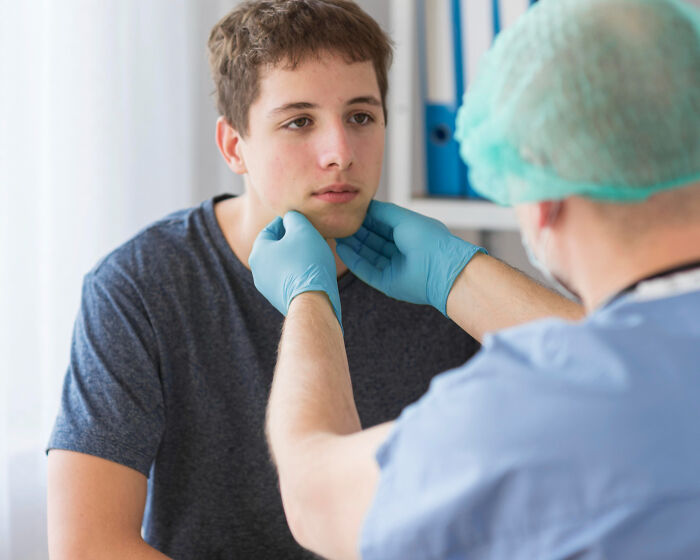 Doctor in gloves examining young patient's face in a medical office, highlighting patients under the effects of anesthesia.
