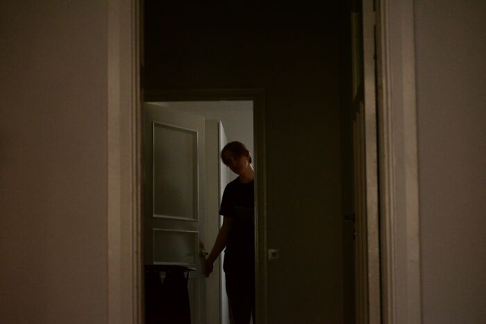 Person standing in a dark hallway captured by surveillance camera, creating an eerie and unsettling atmosphere.