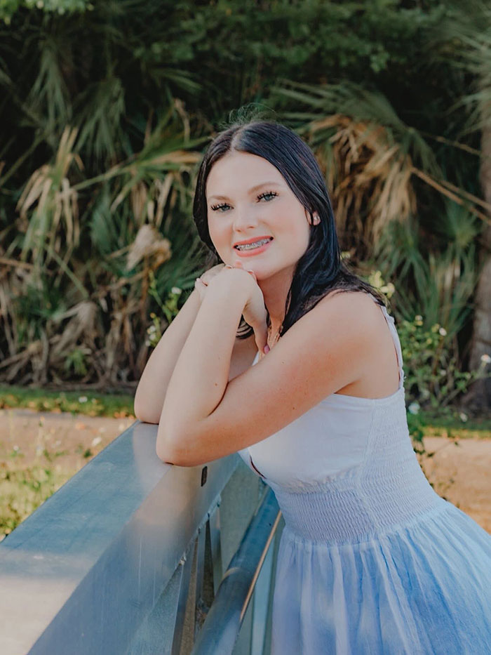 Teen stepsibling under investigation after body found stuffed under bed on Carnival Cruise, young woman posing outdoors in white dress. Teen stepsibling under investigation after body found stuffed under bed on Carnival Cruise, young woman posing outdoors in white dress.