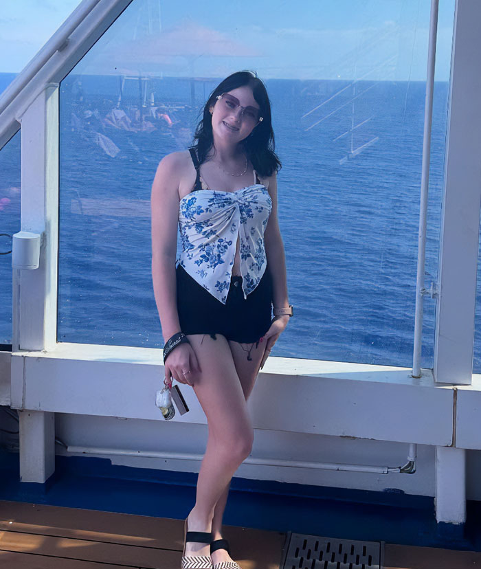Teen girl smiling on cruise ship deck with ocean in background, related to father affair with 15YO babysitter case. Teen girl smiling on cruise ship deck with ocean in background, related to father affair with 15YO babysitter case.