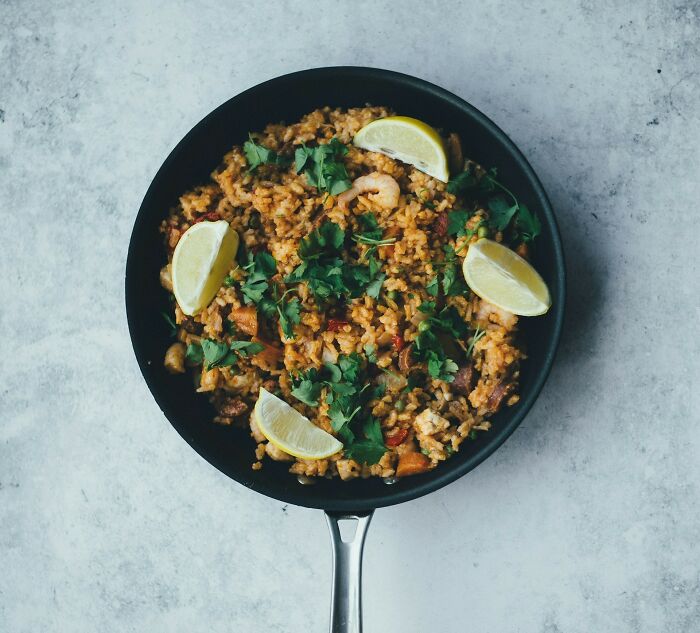 Skillet filled with cooked rice, shrimp, herbs, and lemon wedges, illustrating common home cook mistakes in kitchen prep.