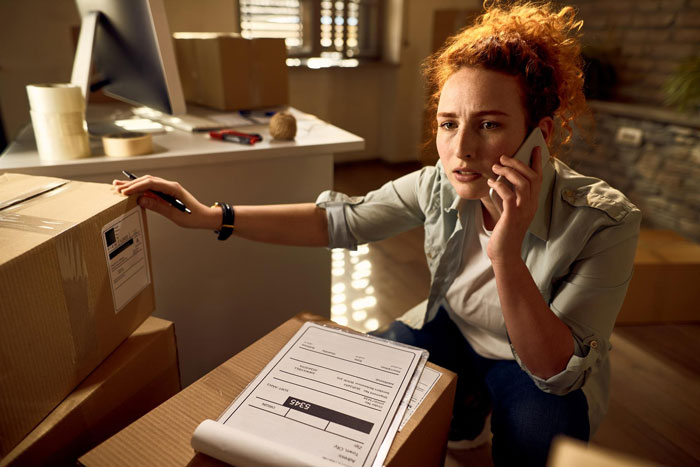 Woman organizing aunt crib storage baby items at home, talking on the phone while checking boxes and paperwork. Woman organizing aunt crib storage baby items at home, talking on the phone while checking boxes and paperwork.