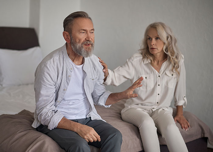 Older couple having a tense conversation on bed illustrating wild family dramas that make relatives look normal.
