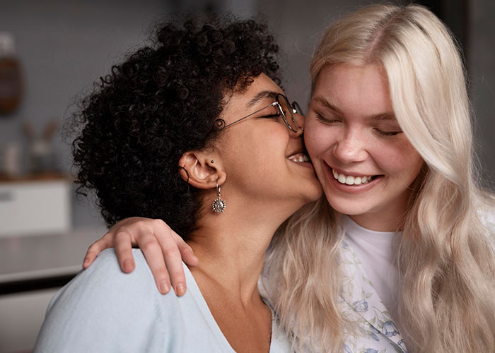Two women sharing a joyful moment, highlighting wild family dramas that make your relatives seem normal and relatable.