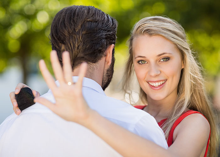 Young woman smiling and embracing a man outdoors, capturing a moment of family drama in a casual setting.