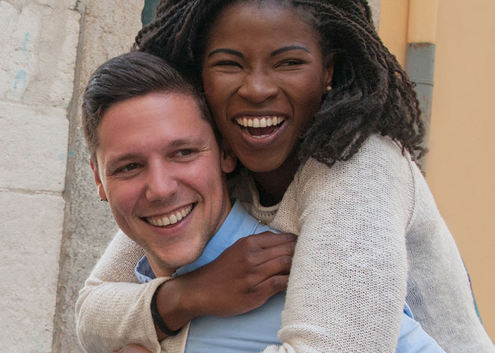 Happy interracial couple sharing a joyful moment outdoors, illustrating wild family dramas that make relatives look normal.