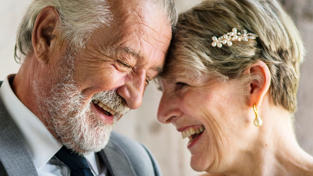 Elderly couple laughing together, sharing a joyful moment reflecting wild family dramas and close relationships.
