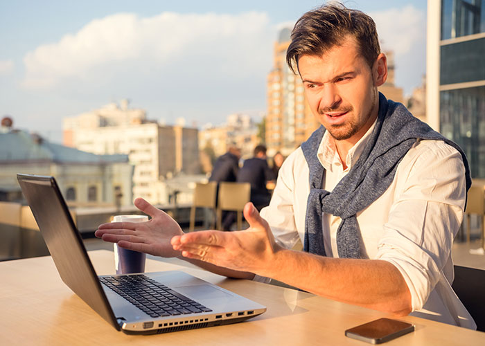 Man reacting with disbelief at laptop screen, capturing a crazy moment that wasn’t what it looked like outdoors.