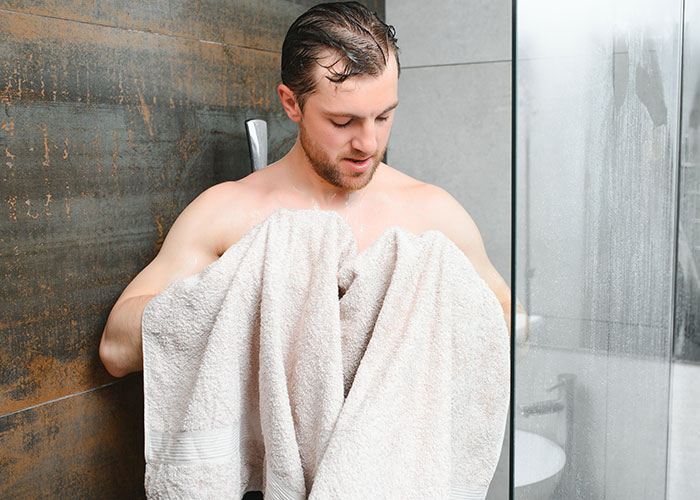 Man drying himself with a towel in a shower, capturing one of the crazy moments that weren’t what they looked like.