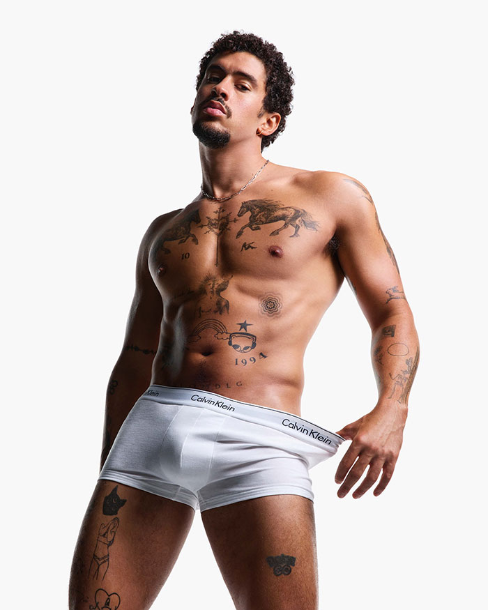 Male celebrity with tattoos posing shirtless in white Calvin Klein underwear, revealing more than expected in 2025 frenzy.