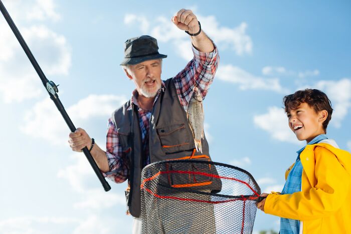 Older man and boy fishing together outdoors, experiencing one of the craziest coincidences with a caught fish.
