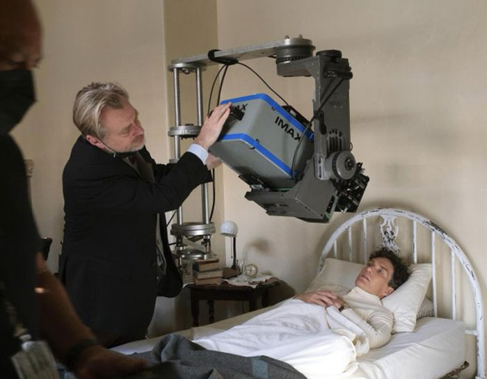 Director adjusting IMAX camera over actor lying in bed in a behind-the-scenes photo from unhinged moments.