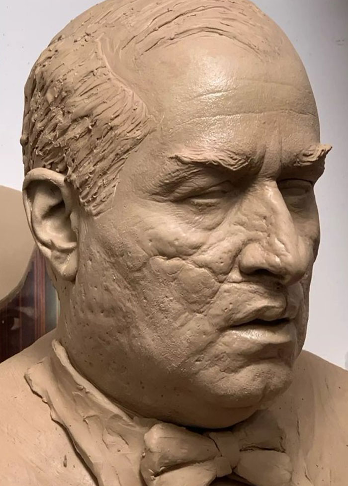 Close-up of an unhinged behind-the-scenes clay sculpture face with detailed wrinkles and textured skin.