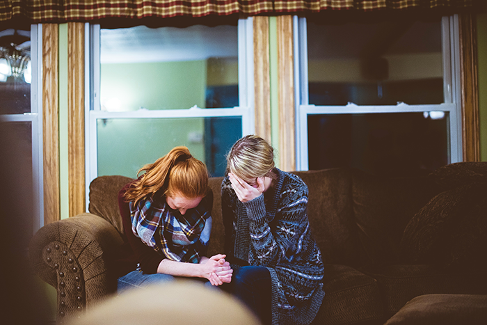 A teenage girl and her mother sitting on a couch looking upset, reflecting a parenting conflict about buying food. A teenage girl and her mother sitting on a couch looking upset, reflecting a parenting conflict about buying food.