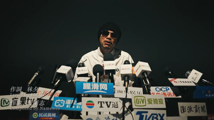 Man in sunglasses and hat speaking at a press conference about body of provocative influencer found in hotel bathtub. Man in sunglasses and hat speaking at a press conference about body of provocative influencer found in hotel bathtub.