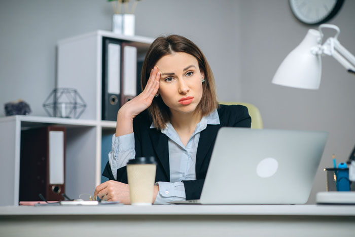 Female software developer looking frustrated at her laptop during a client meeting, highlighting workplace gender bias.