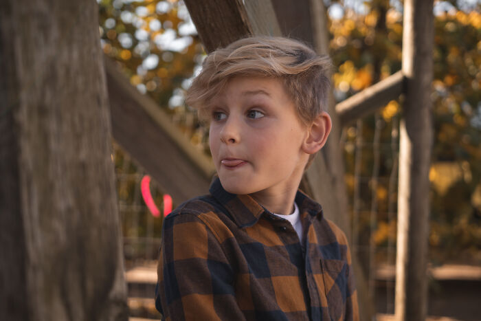 Young boy in a plaid shirt outdoors, representing themes of people who regret having kids and parenting challenges.