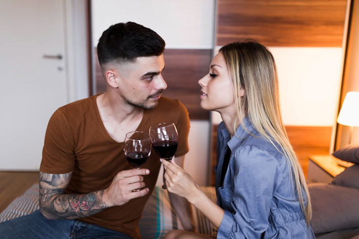 Couple sharing wine on vacation, the woman looking suspicious as the boyfriend appears distracted and unfaithful. Couple sharing wine on vacation, the woman looking suspicious as the boyfriend appears distracted and unfaithful.