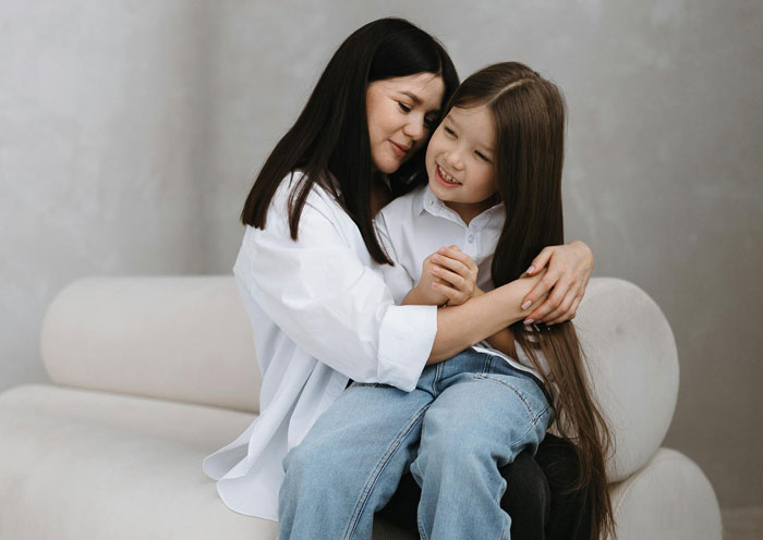 Mother and daughter sharing a warm hug on a couch, illustrating comforting moments amid boyfriend daughter snitch drama.
