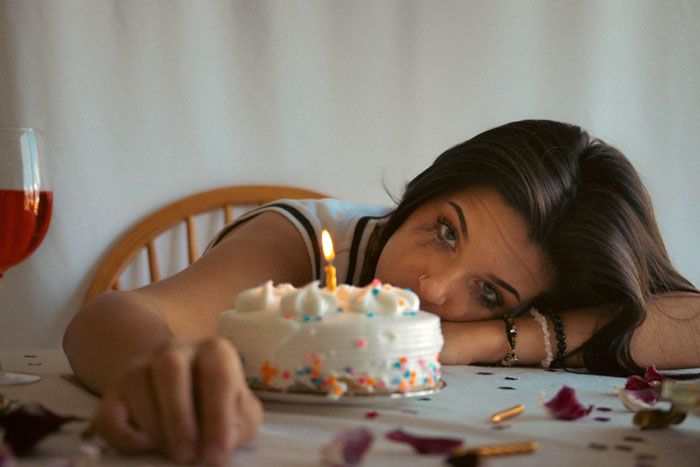 Woman looking sad with makeup smudged at birthday cake with one candle, highlighting forgotten birthday frustration. Woman looking sad with makeup smudged at birthday cake with one candle, highlighting forgotten birthday frustration.